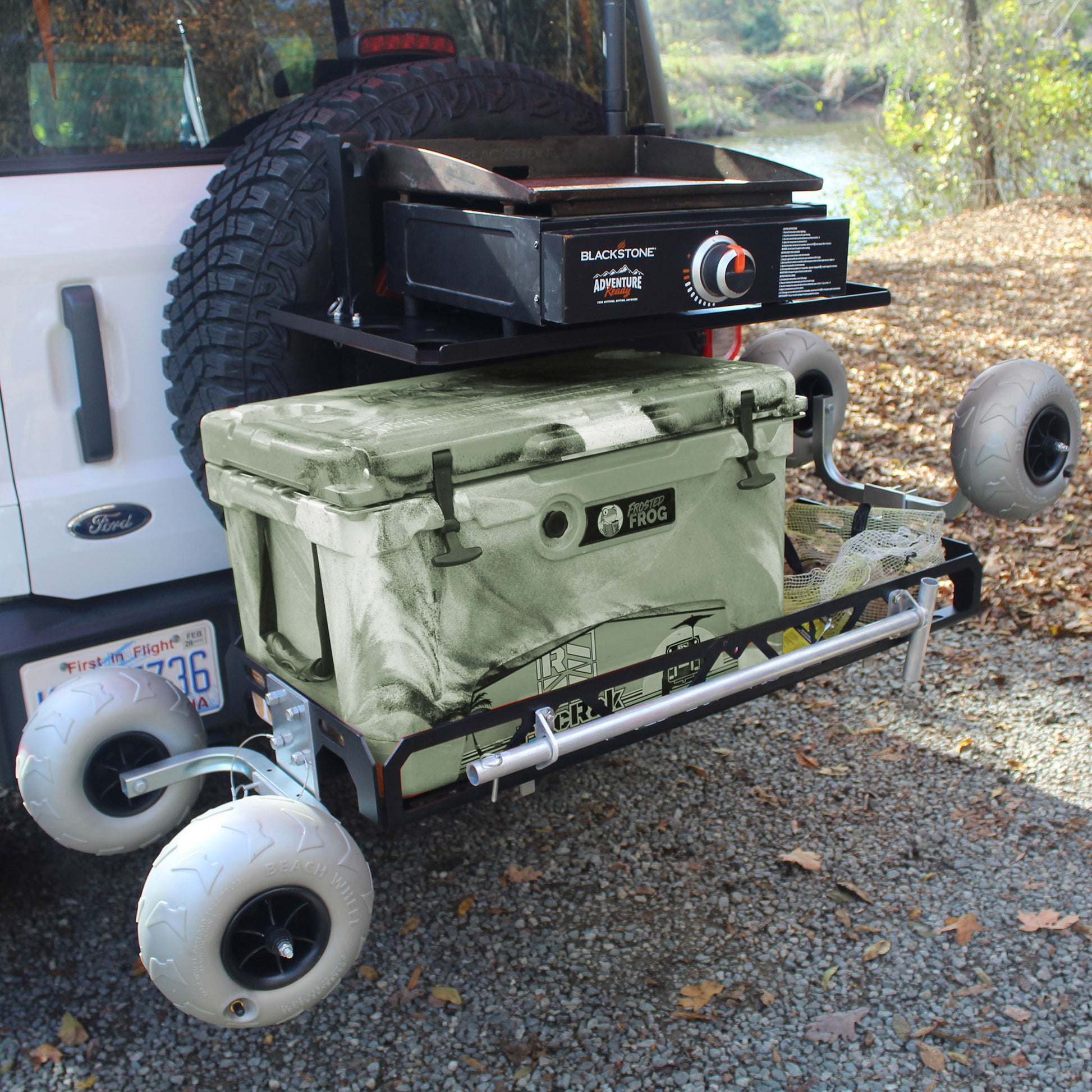 Cargo carrier with Camouflage cooler on wheels attached to a vehicle with Blackstone grill on top