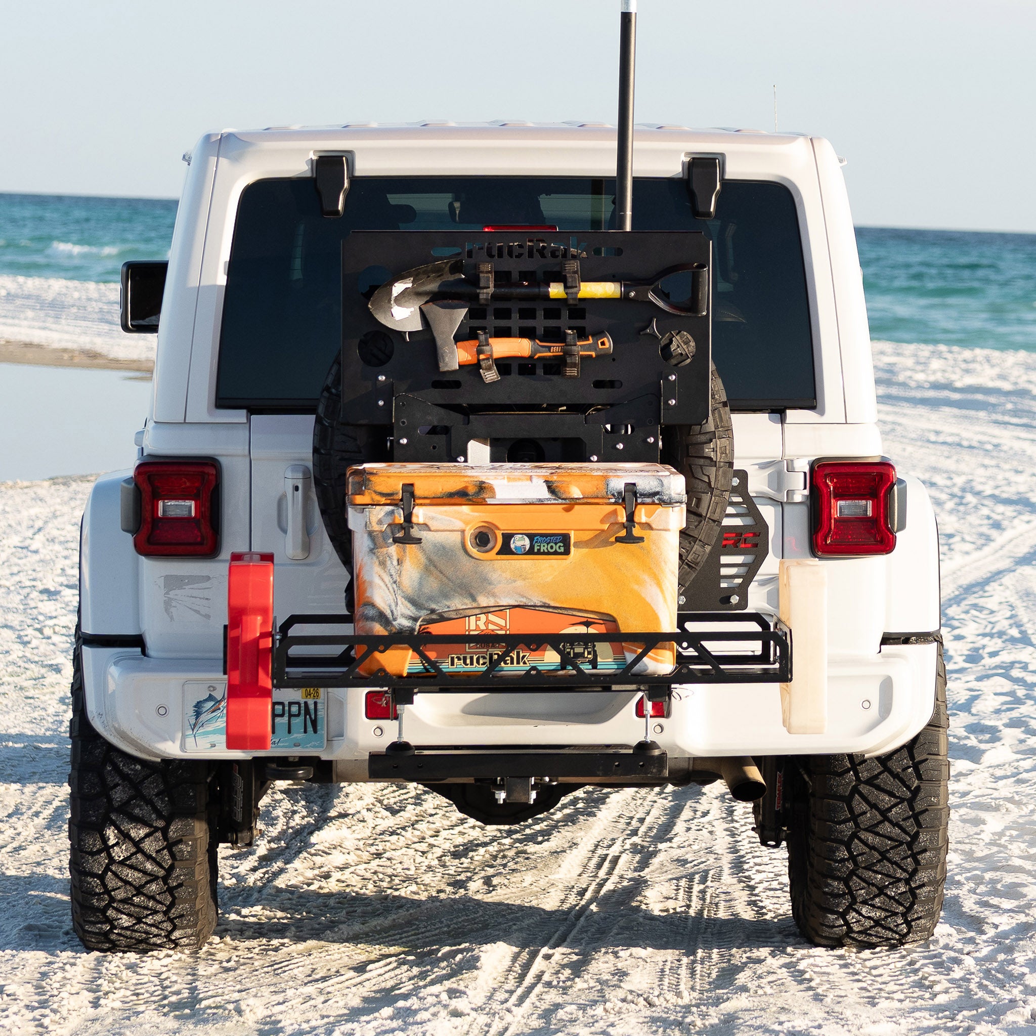 White Jeep Wrangler on a sandy beach with a cooler attached to the back
