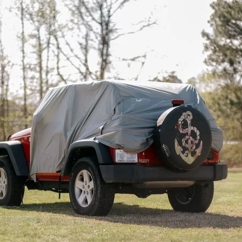 Jeep with a trail gear oasis 2-in-one rain cover and tailgate shade on the back and a spare tire 